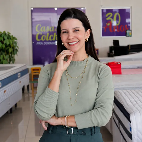 Atendente da Casa dos Colchões em frente ao cartaz de 30 anos da loja