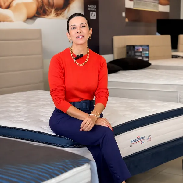 Atendente da Casa dos Colchões sentada em um colchão de molas do showroom